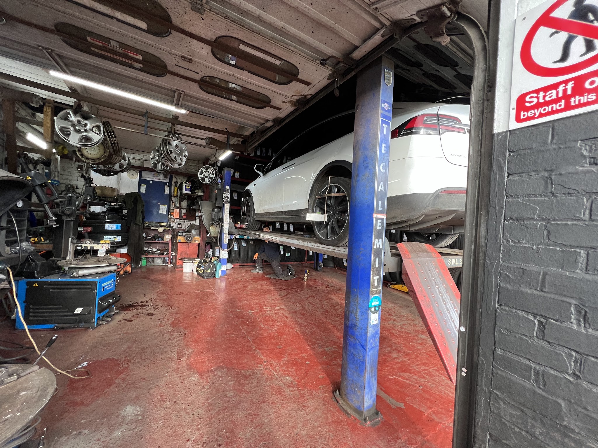 Inside the Stoke Tyres workshop: tyre changing machines, a car up on the lift and wheels on the wall