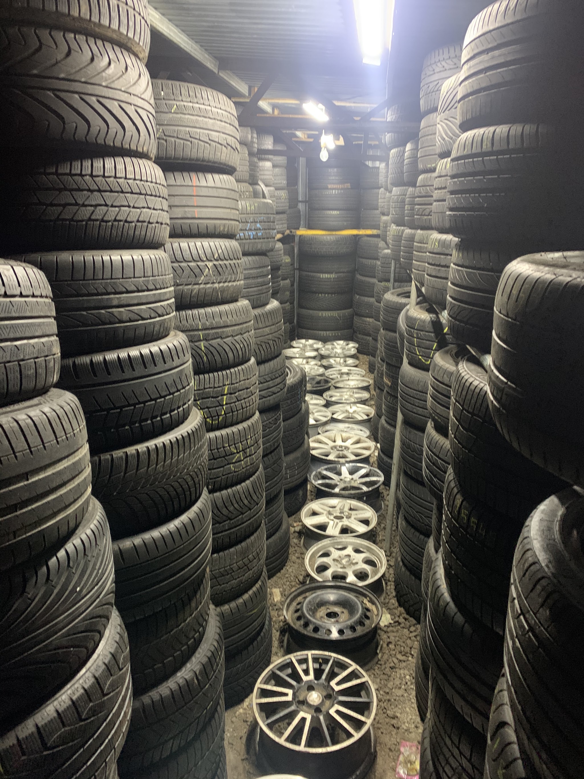 An aisle stacked high with part worn tyres and alloy wheels in the Stoke Tyres store